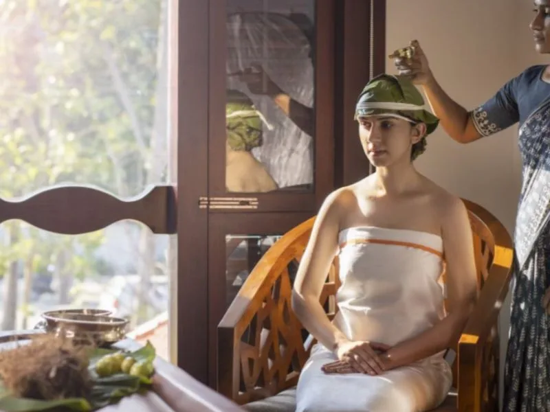 Therapist pouring warm Ayurvedic oil for a traditional massage treatment